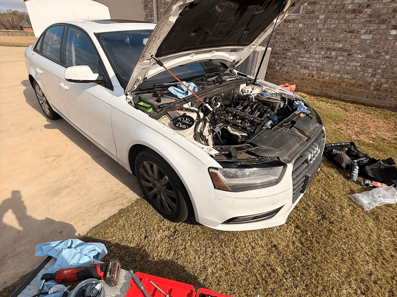mobile mechanic working under the hood in a driveway