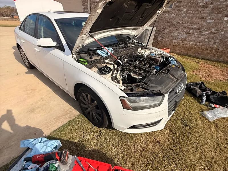 mobile mechanic working under the hood in a driveway